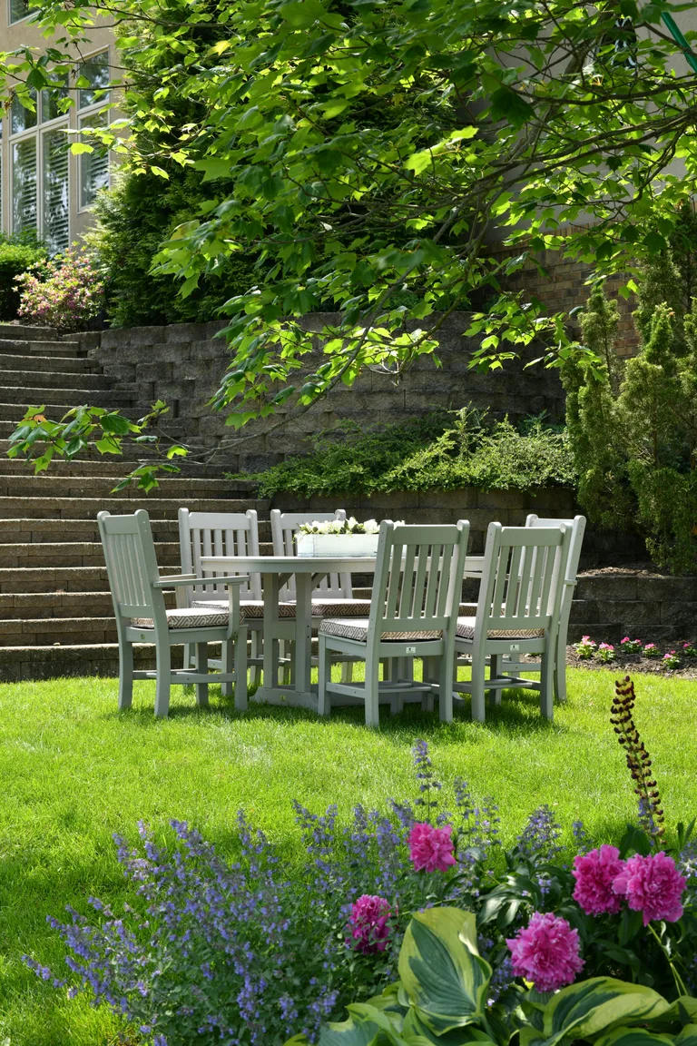 Jardin paysager avec terrasse, pelouse, arbres et massifs fleuris